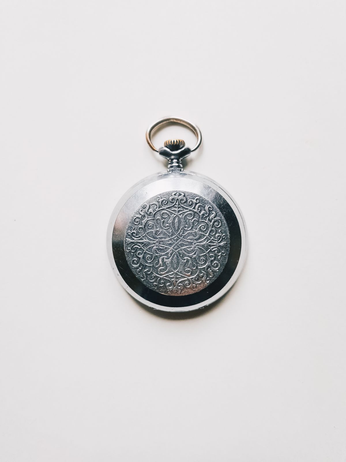 Boîtier fermé d’une montre de poche, orné de motifs gravés.